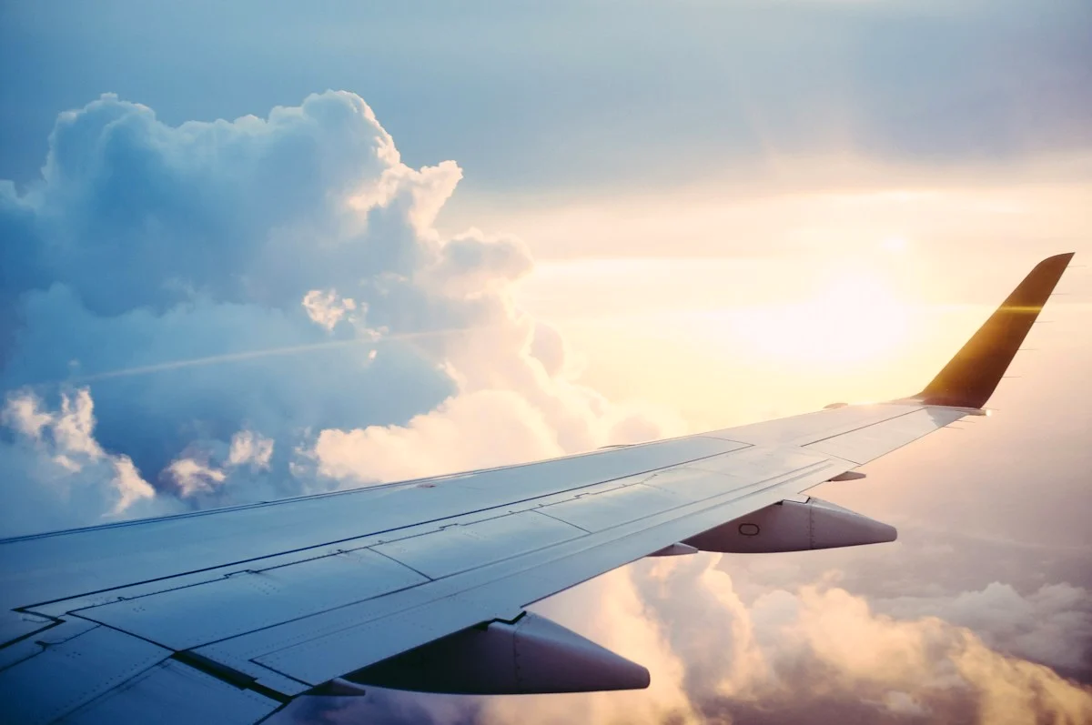Vista da janela de um avião acima das nuvens ao entardecer